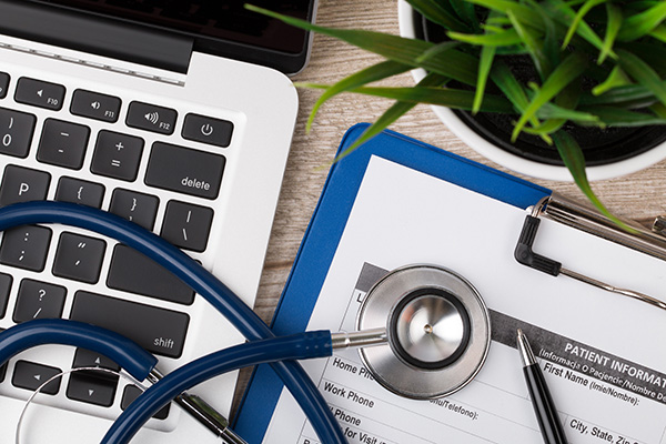 A laptop and a paper medical record on a desk